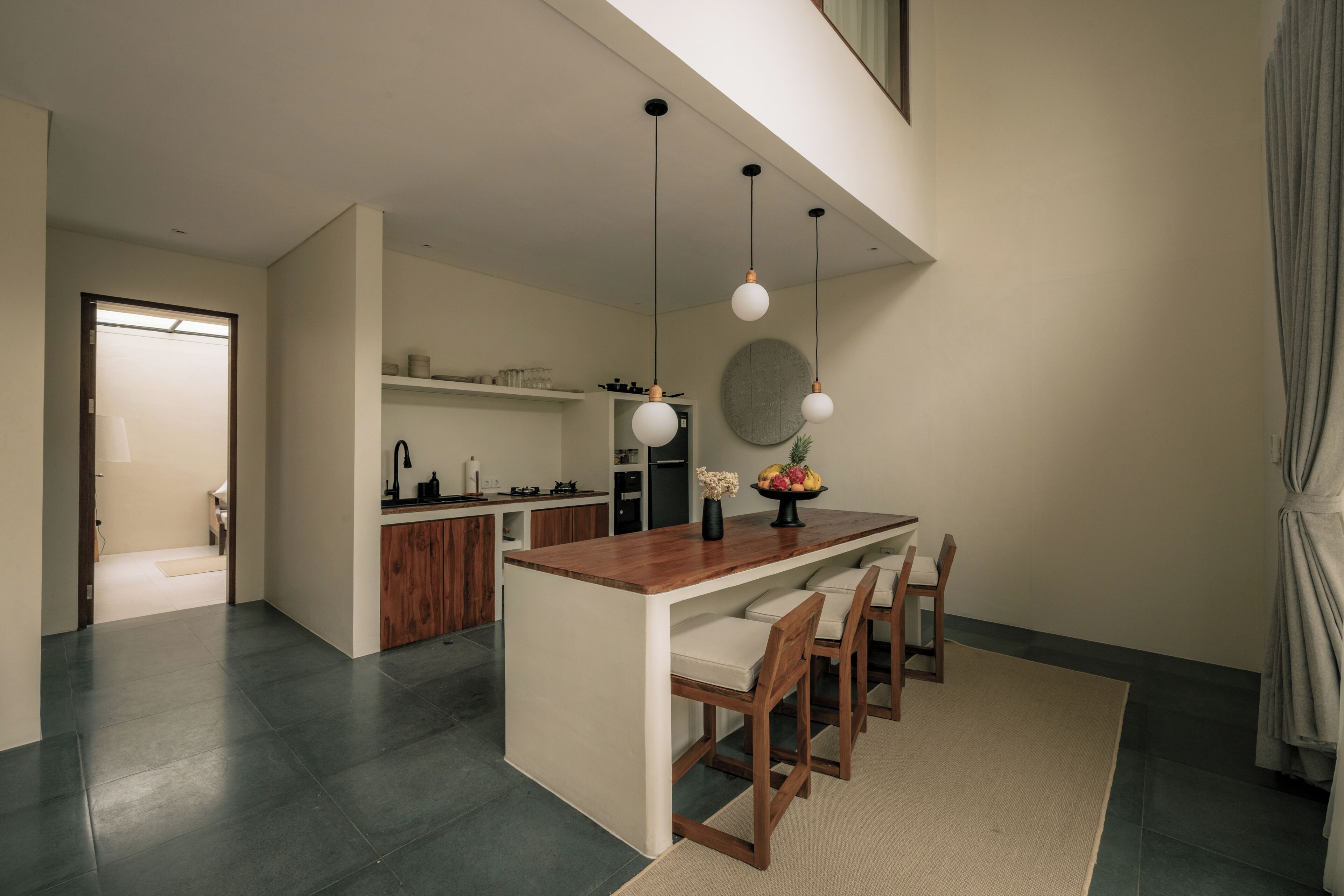 A modern kitchen with a central island, pendant lighting, and a view to the dining area.