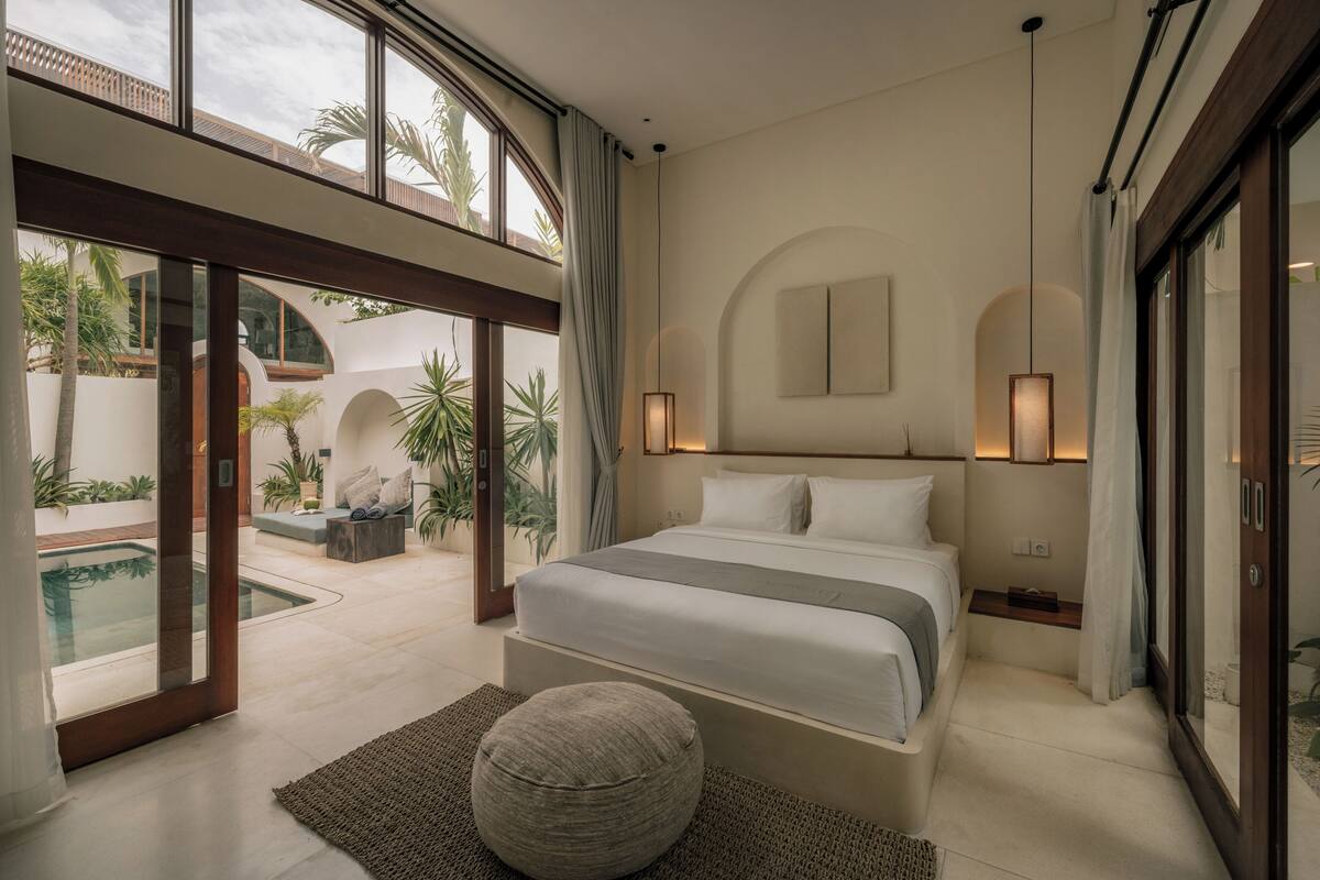 Une chambre moderne avec un grand lit, une vue sur une piscine et un balcon.