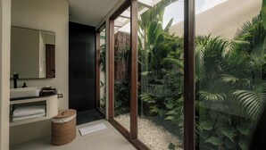 Ein modernes Badezimmer mit einem großen Spiegel, einem Waschbecken und einer kleinen Mülleimer.