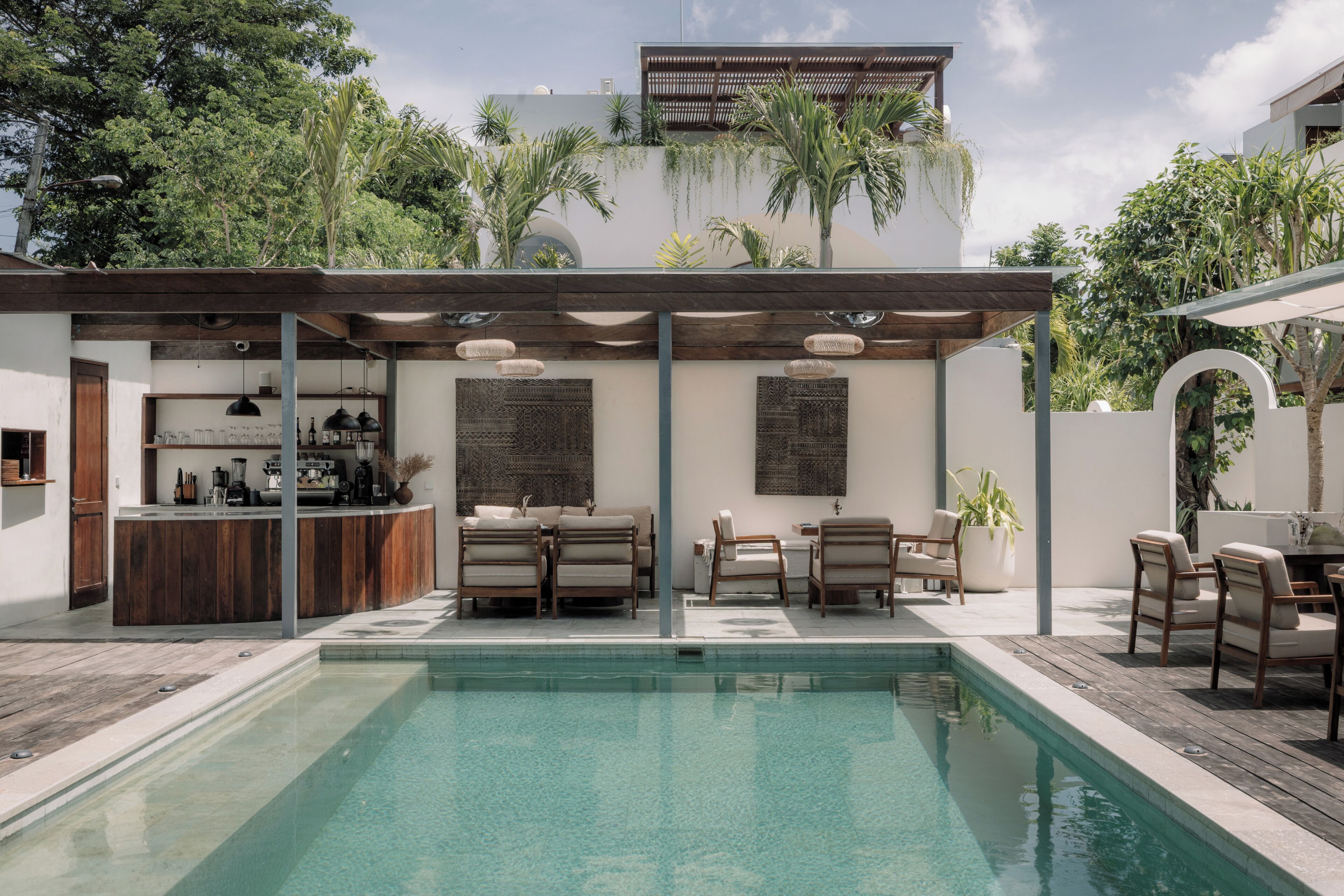 Una zona de piscina con bar, asientos y una pérgola.