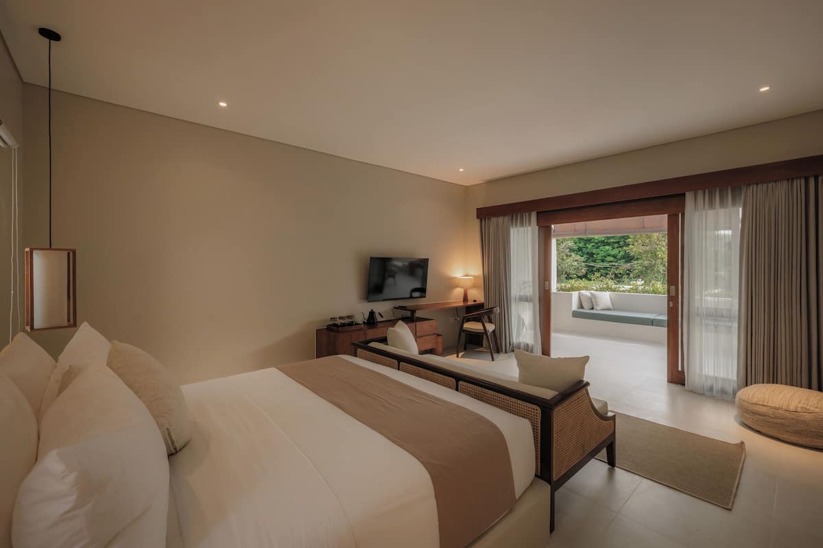 Une chambre d’hôtel avec un grand lit, un bureau avec une chaise, une télévision et une vue sur l’extérieur.