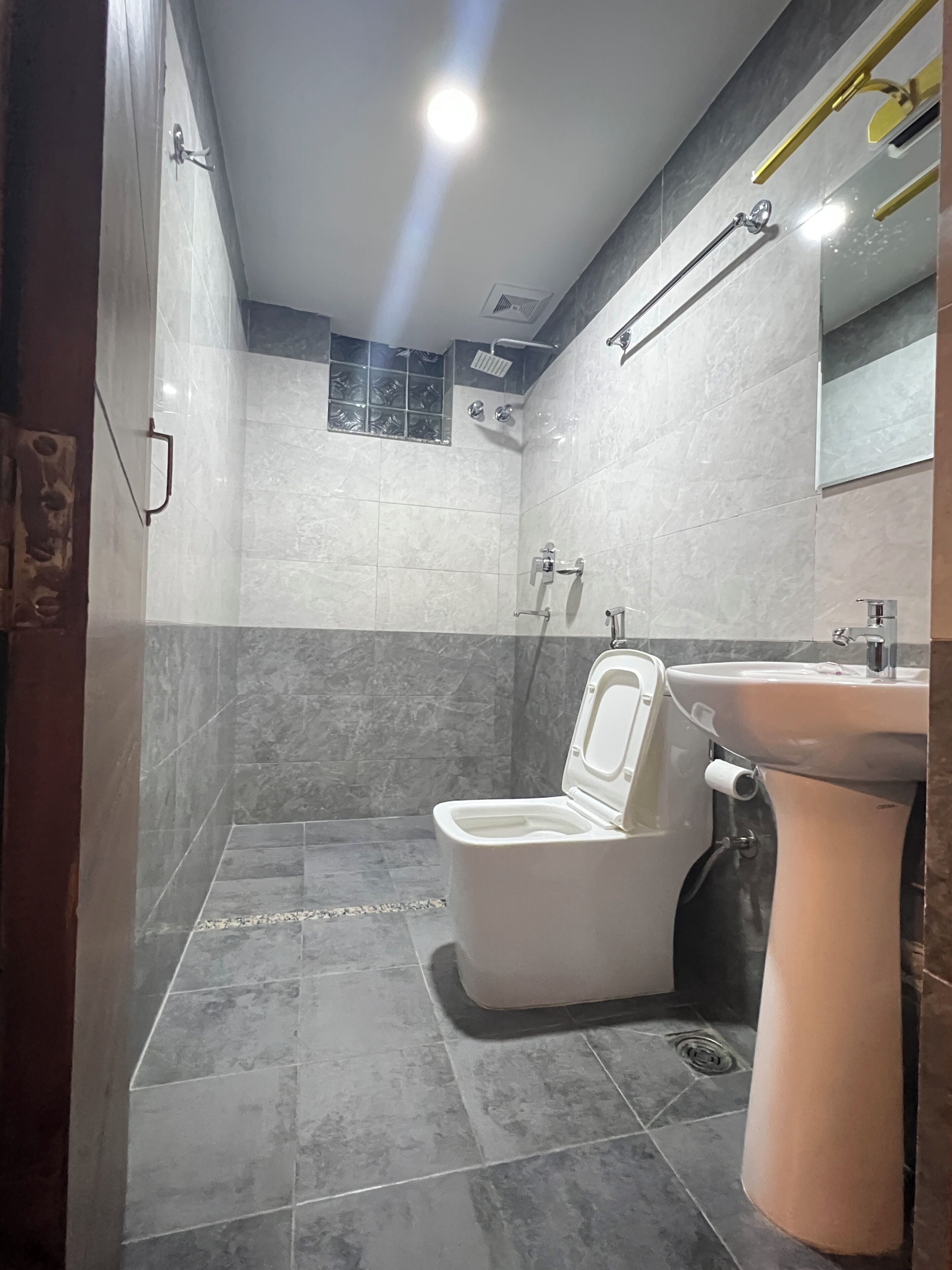Un baño con inodoro, lavamanos, ducha y ventana con vistas.