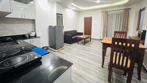 Una cocina moderna con estufa integrada, refrigerador y comedor con mesa y sillas de madera.