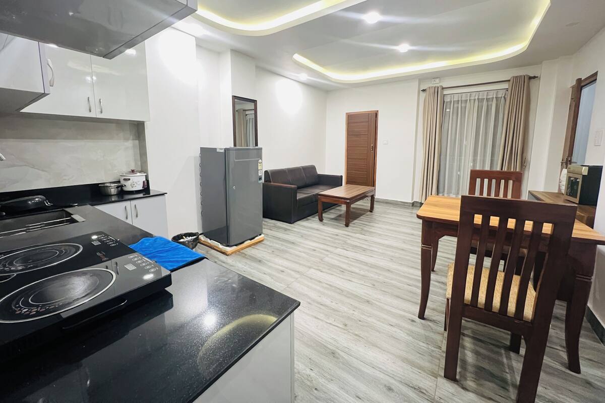A modern kitchen with a built-in stove, a refrigerator, and a dining area with a wooden table and chairs.