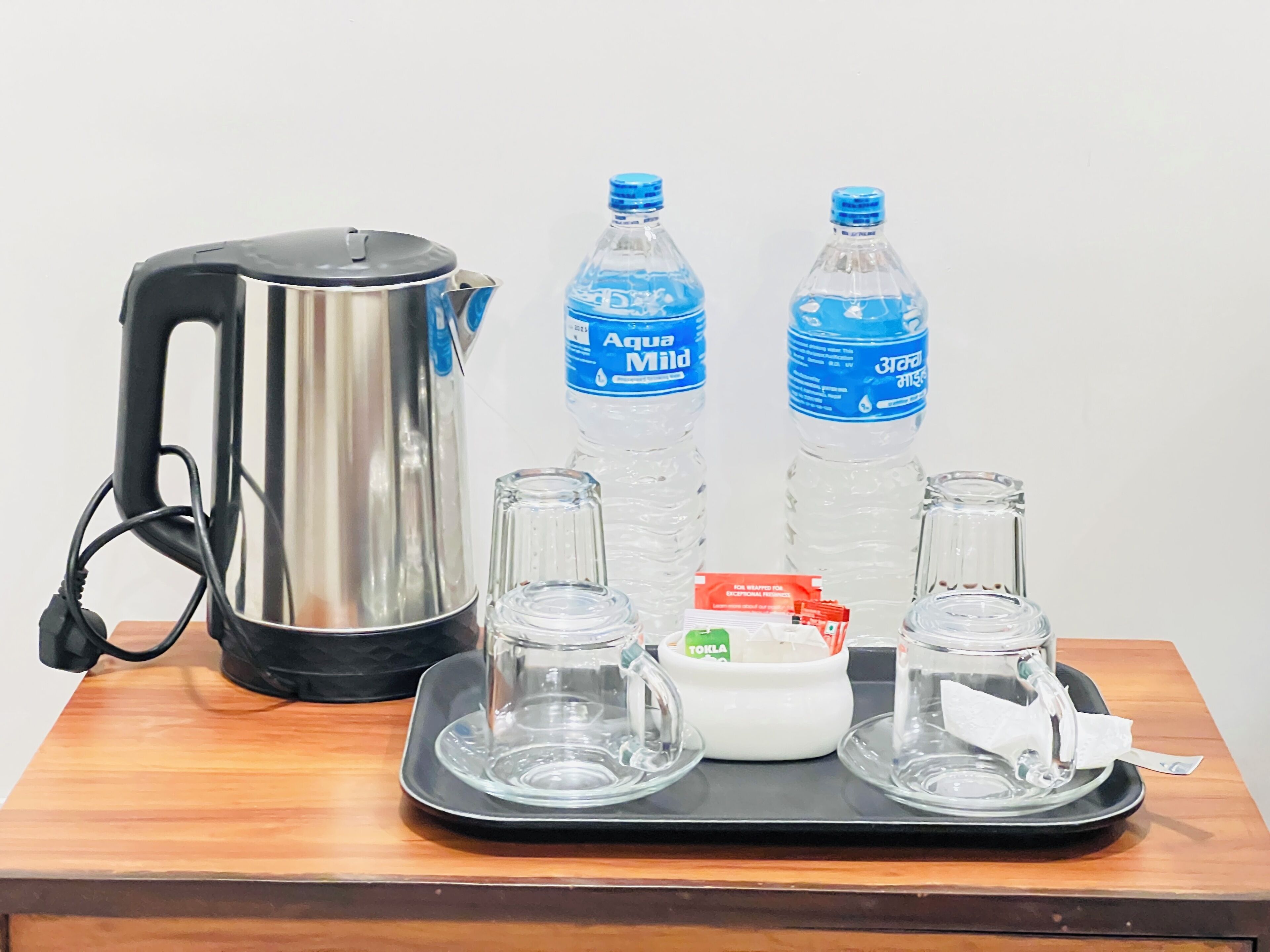 Una mesa con una tetera, dos botellas de agua, un recipiente pequeño y dos vasos.
