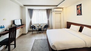 Una habitación de hotel con cama, escritorio, silla y una pequeña mesa con otra silla.