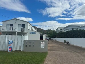 A residential building with a white exterior, a balcony, and a sign indicating a parking sale. - 2Br - Walk to Beach and Dining (North Ward)