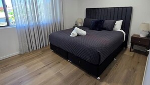 Ein modernes Schlafzimmer mit einem großen Bett, einem Deckenventilator und einem Fenster mit Vorhängen.