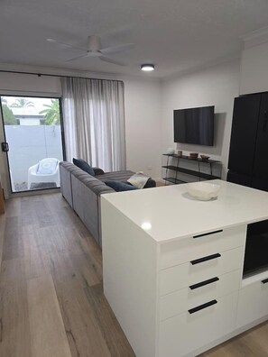 A modern kitchen with a white countertop, a built-in oven, and a television mounted on the wall. - 2Br - Walk to Beach and Dining (North Ward)