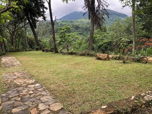 A stone pathway leading through a grassy area with a mountainous backdrop. - Koshi's Lotus room Ella (Bandarawela)