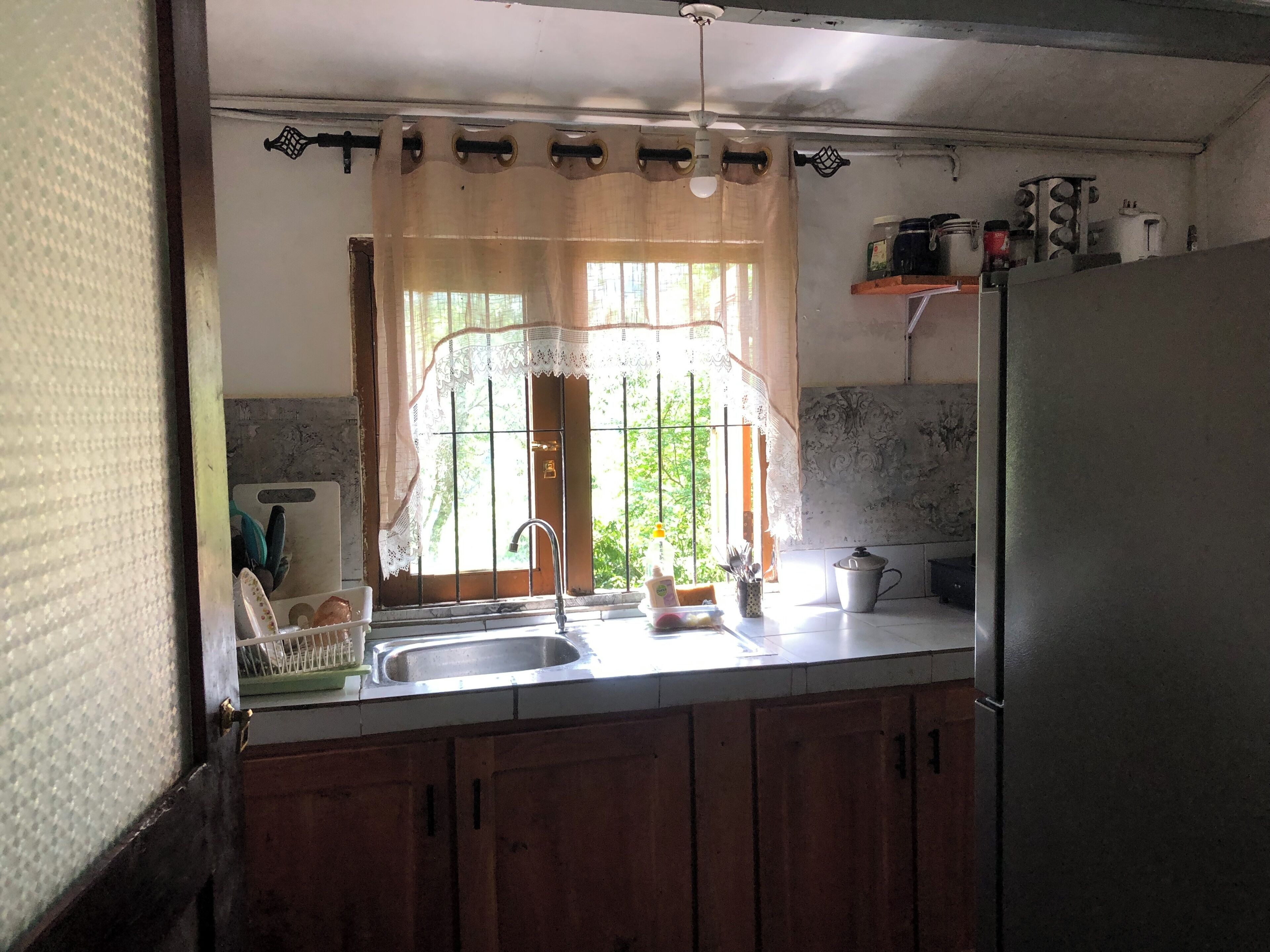 A kitchen with wooden cabinets, a stainless steel sink, and a refrigerator.