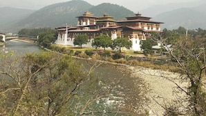 Un grand bâtiment traditionnel à plusieurs niveaux, avec une rivière au premier plan.