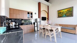 Cozinha moderna com armários de madeira, bancada de mármore e área de jantar com mesa e cadeiras de madeira.