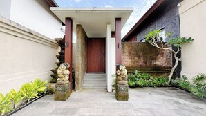 Uma entrada tradicional com porta de madeira, estátuas de pedra e um pequeno jardim.