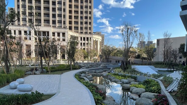 Un giardino curato con un vialetto sinuoso, uno stagno e grandi massi.