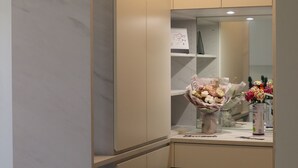 Una cucina moderna con ripiani in marmo, forno a incasso e lavello. Presente una piccola isola con un vaso di fiori e una macchina da caffè.