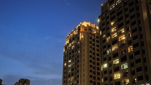 Un edificio alto con molti piani e balconi, circondato da altri edifici.