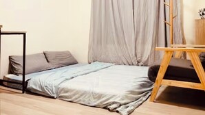Una stanza piccola con un letto, un tavolo di legno e un attaccapanni.