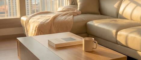 A modern living room with a sofa, a coffee table, a book, and a mug.