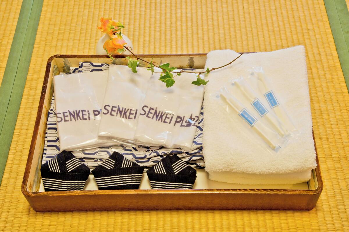 A wooden box containing neatly folded towels, a pair of striped socks, and a small decorative item.
