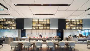 A modern restaurant with a central dining area featuring round tables and chairs, surrounded by shelves displaying various dishes and kitchenware. - Modena by Fraser Nanjing (Nanjing)