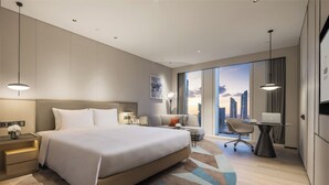 A modern hotel room with a large bed, a desk, and a view of the city skyline. - Modena by Fraser Nanjing (Nanjing)