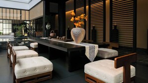 Un espace de restauration moderne, avec une longue table, des chaises rembourrées et un vase décoratif.