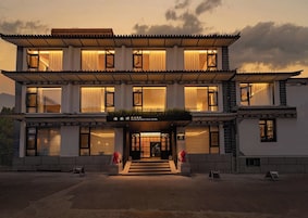 Un hotel boutique de dos pisos, con estilo arquitectónico tradicional, que destaca por su entrada con escalones y un letrero.