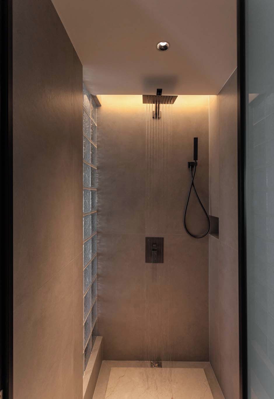 Una ducha moderna con cerramiento de vidrio, panel de control y cabezal de ducha de mano.