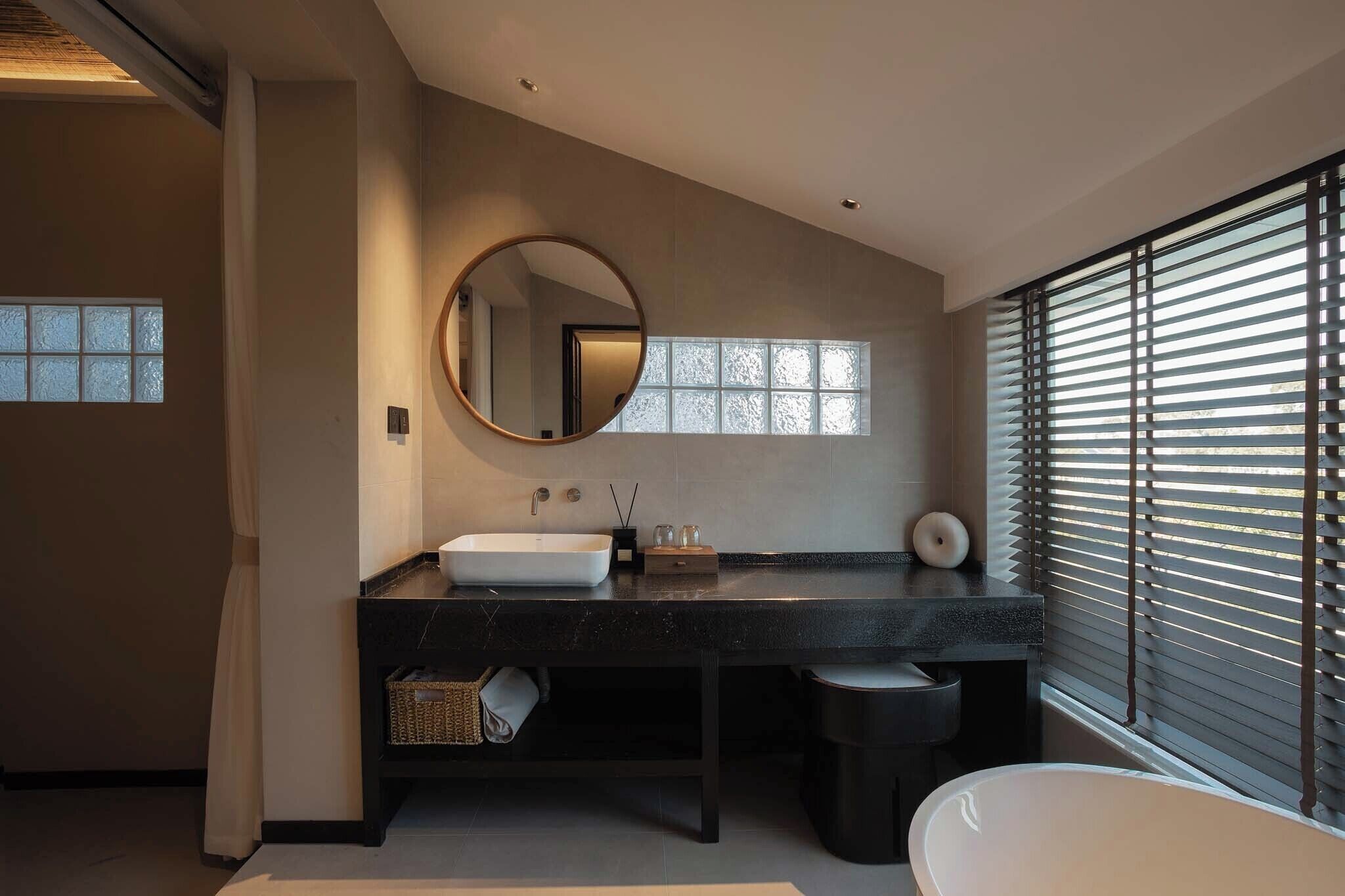 A modern bathroom with a large mirror, a white sink, and a bathtub.