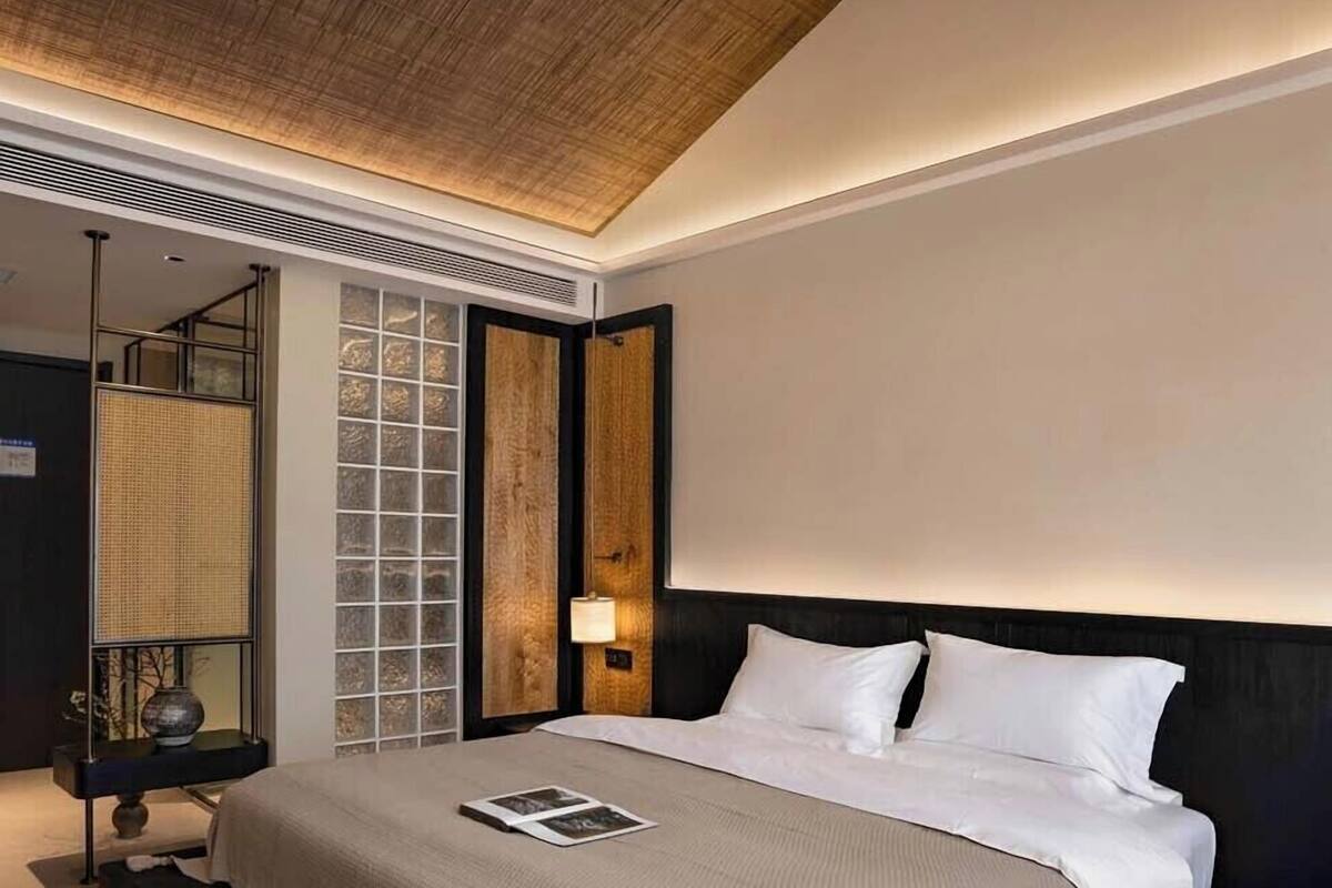 Een moderne slaapkamer met een groot bed, houten plafond en uitzicht over de stad.