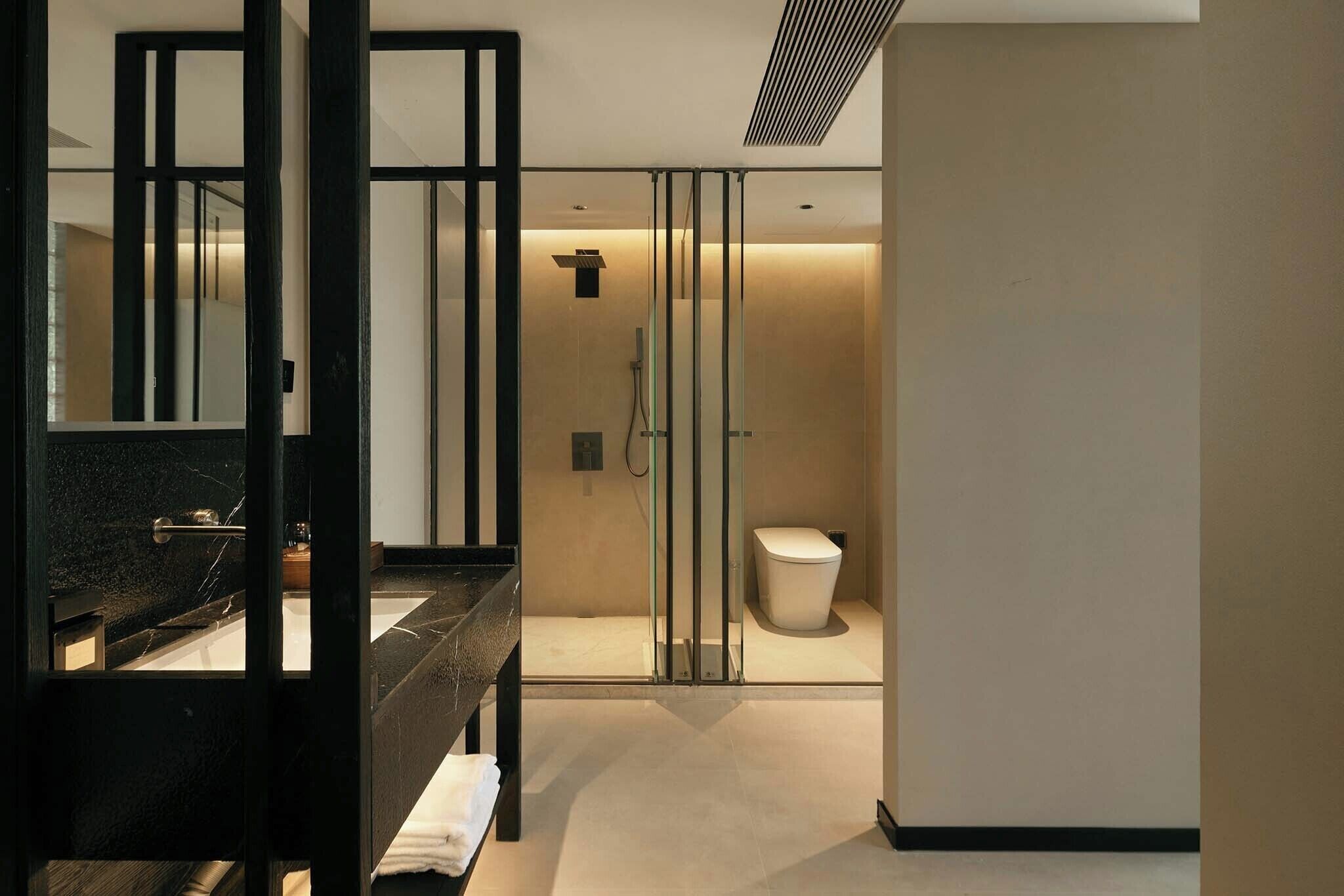 A modern bathroom with a glass shower enclosure, a black vanity, and a white toilet.