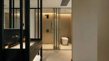 A modern bathroom with a glass shower enclosure, a black vanity, and a white toilet.