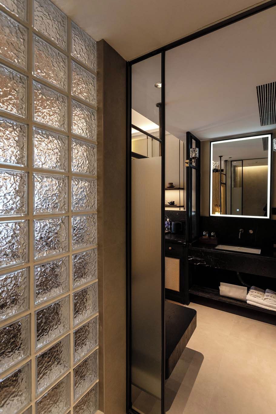 A modern bathroom with a glass partition, a large mirror, and a black vanity.