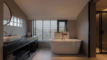 Un baño moderno con una bañera grande, un tocador con espejo y una ventana con persianas.