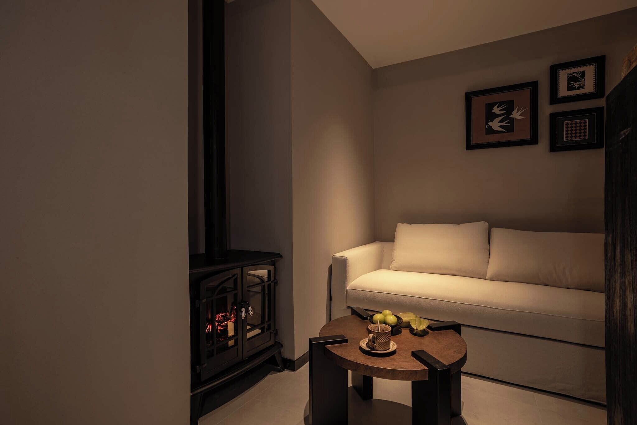 A cozy living room with a sofa, a small table with fruits, and a fireplace.