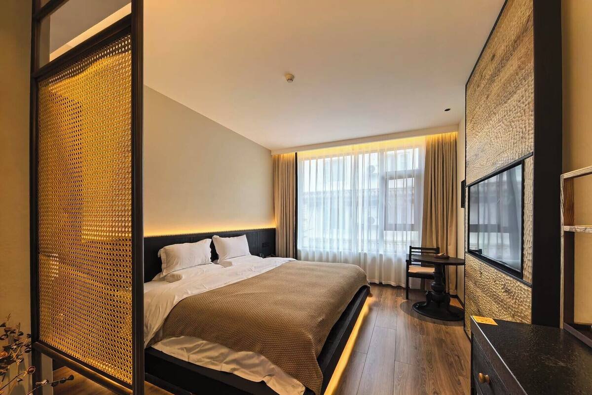 Een moderne hotelkamer met een groot bed, een televisie en een houten vloer.