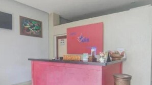 A reception desk with a red counter, a framed abstract painting on the wall, and a trash can to the right. - Hotel Star 88 (Sleman)
