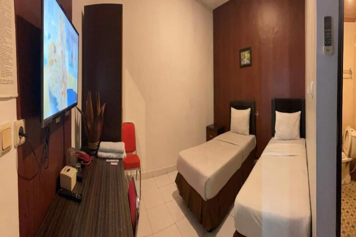A hotel room with two beds, a TV, a desk, and a chair.