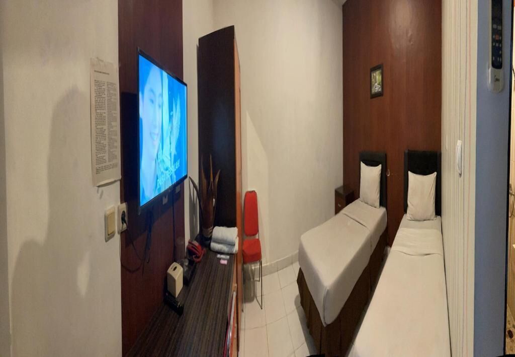 A hotel room with a television, a desk, a chair, a bed, and a small table.