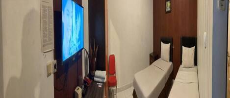 A hotel room with a television, a desk, a chair, a bed, and a small table.