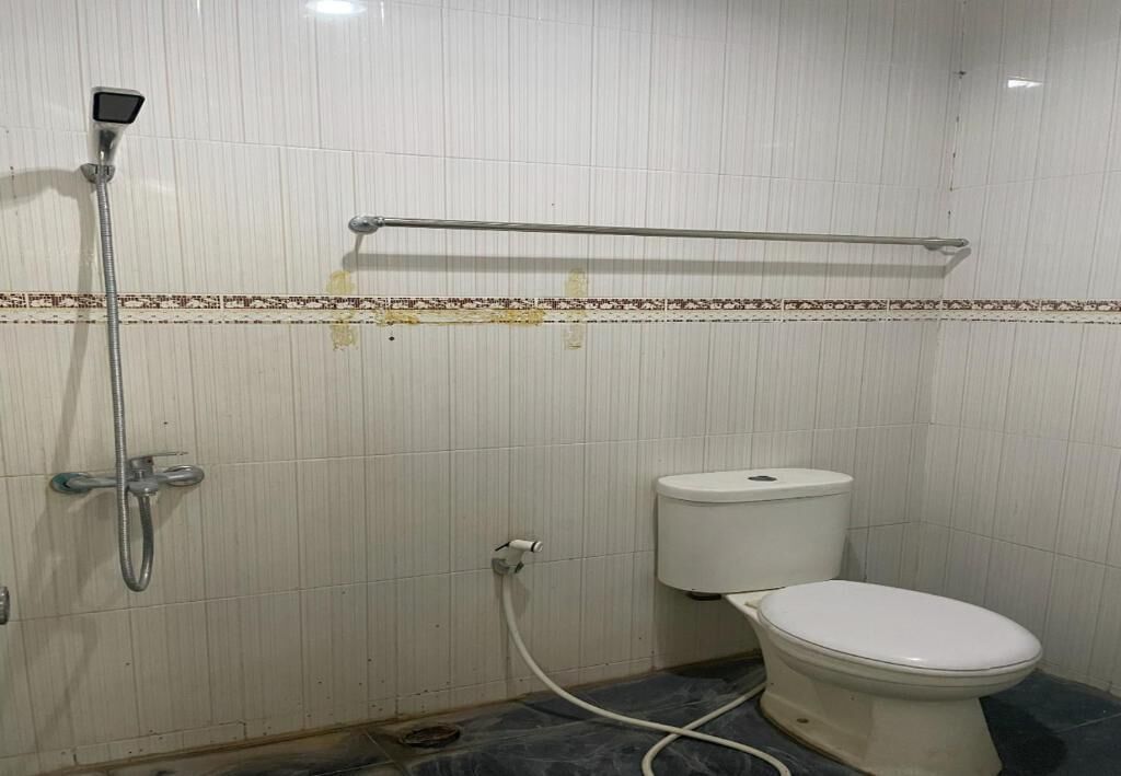 A bathroom with a toilet, a shower, and a towel rack.