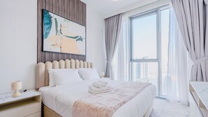 Quarto de hotel com uma cama grande, mesa de cabeceira, cortinas e vista para a cidade.