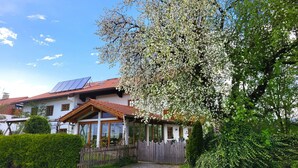 Et hus med solpaneler på taget, et træhegn og en have.
