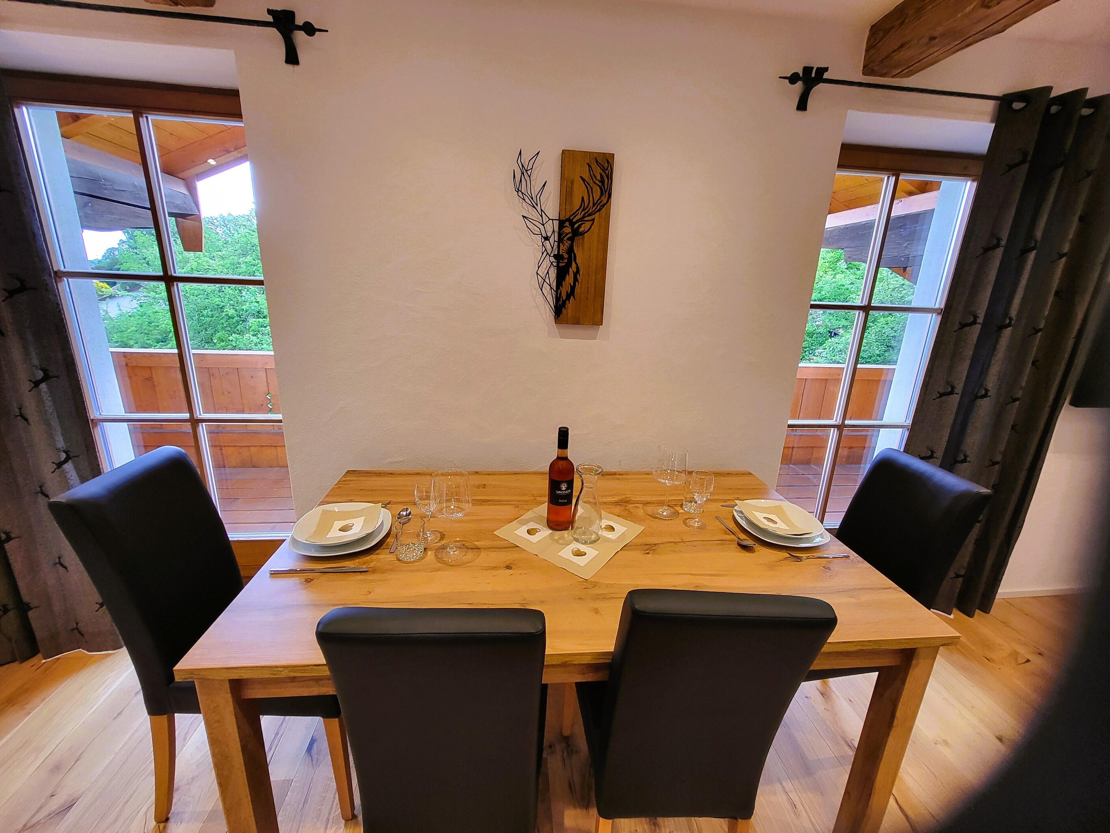 A dining table with four chairs, a bottle of wine, and several glasses.