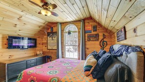 Un dormitorio rústico de cabaña con cama, escritorio y televisión.