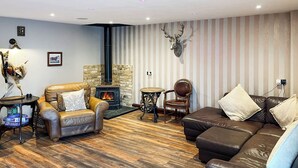 A cozy living room with a fireplace, leather sofas, and a deer head decoration. - 4 bedroom accommodation in Bishop Auckland (Bishop Auckland)