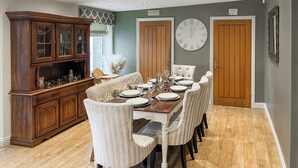 A dining room with a wooden table set for six, flanked by two doors and a large clock on the wall. - 4 bedroom accommodation in Bishop Auckland (Bishop Auckland)