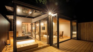 Un espacio exterior moderno con jacuzzi, puertas de cristal y terraza de madera.