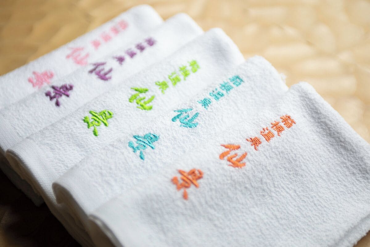 A stack of towels with embroidered text in different colors.